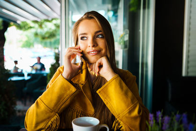 Portrait of a young woman drinking from mobile phone