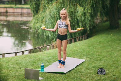 Girl with laptop exercising on field