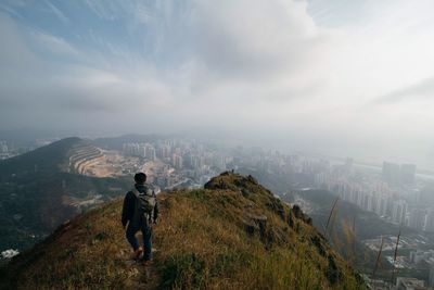 High angle view of hiker walking on mountain top against cityscape