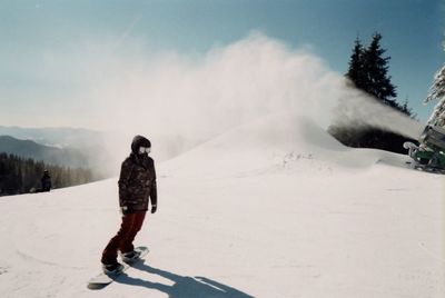 Rear view of man on snowcapped mountain against sky