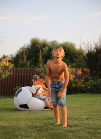 Portrait of boy teasing while standing on grass in yard