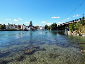 Bridge over river in city against blue sky