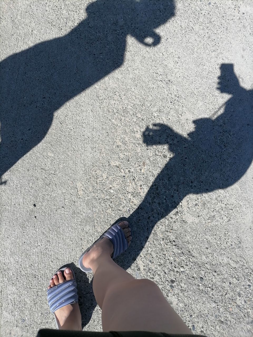 shadow, sunlight, high angle view, blue, low section, lifestyles, one person, day, nature, human leg, leisure activity, black, focus on shadow, adult, women, city, men, outdoors, road, standing, street, hand, limb, human limb, personal perspective, shoe, sunny, footwear, sand, casual clothing