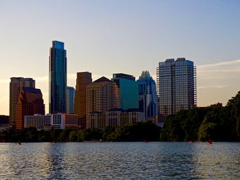 Buildings by river against sky in city