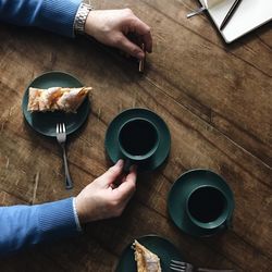 Midsection of man holding coffee cup on table