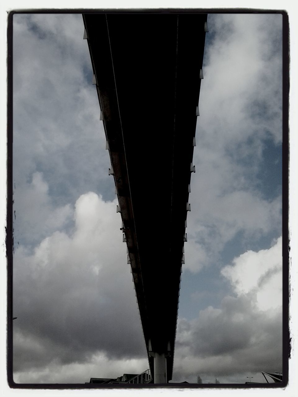 sky, low angle view, transfer print, architecture, built structure, cloud - sky, cloudy, auto post production filter, cloud, connection, bridge - man made structure, building exterior, engineering, outdoors, day, weather, transportation, overcast, city, bridge