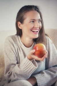 Portrait of young woman holding apple at home