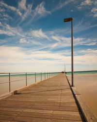 Wooden pier over sea against sky