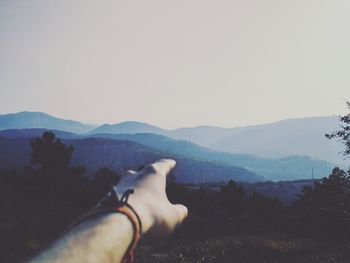 Low section of man on mountain against clear sky