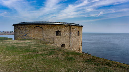 Old building by sea against sky