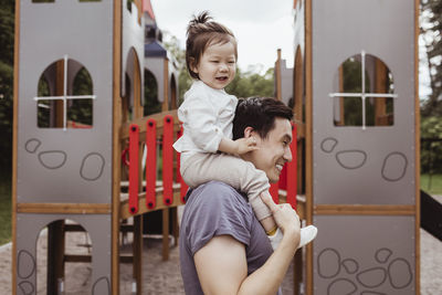 Father carrying baby son shoulder in park