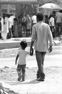 Rear view of boys walking on road