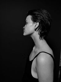 Side view of young woman against black background
