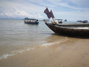 Fishing boat on beach against sky