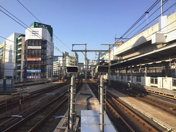 Railroad tracks in city against clear sky