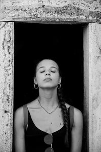 Portrait of young woman standing against wall