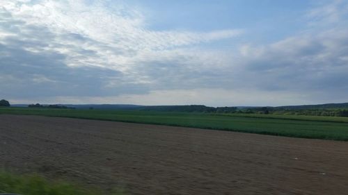 Scenic view of field against cloudy sky