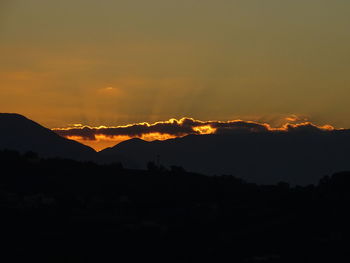 Scenic view of silhouette mountains against orange sky