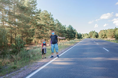 People on road amidst trees against sky