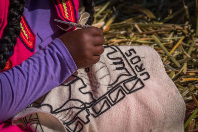 Midsection of woman making embroidery on textile