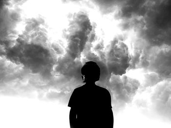 Low angle view of silhouette man standing against cloudy sky
