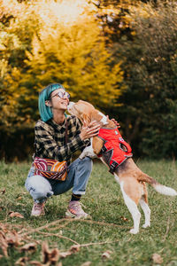 Side view of woman with dog on grassy field