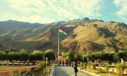 People standing on pathway with indian flag against mountains