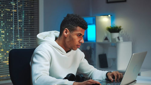 Side view of man using laptop at home