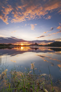 Scenic view of lake against cloudy sky during sunset