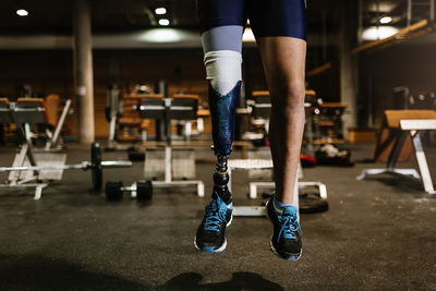 Low section of man with prosthetic leg jumping in gym