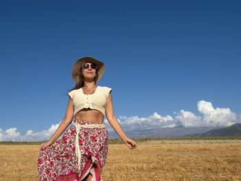 Portrait of woman standing on field against sky