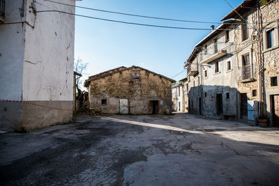 Empty alley amidst buildings in city against sky