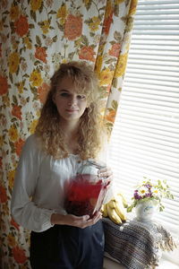 Portrait of beautiful woman standing by window at home