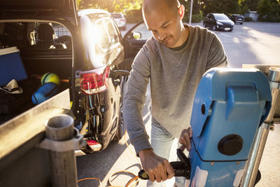 Mature man plugging cable at electric station