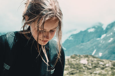 Woman looking down while standing on mountain against sky