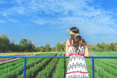 Rear view of woman standing by railing on field