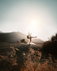 Playful man standing against sky during sunny day