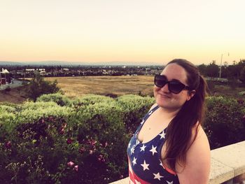 Young woman in sunglasses on landscape against clear sky