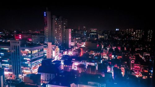 Illuminated buildings in city against sky at night