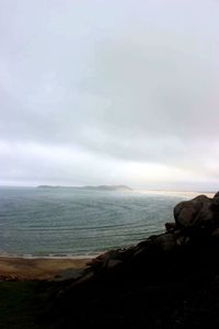 View of calm beach against cloudy sky