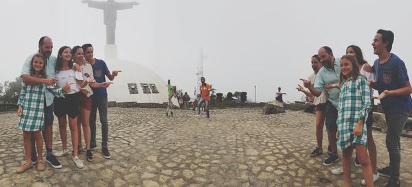 People standing on footpath against sky in city