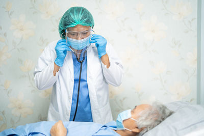 Doctor wearing mask examining patient in hospital