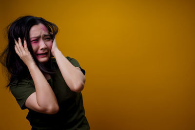 Portrait of beautiful young woman against yellow background