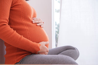 Midsection of woman sitting at home