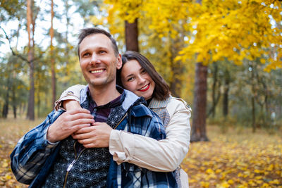 Portrait of smiling young woman standing against trees