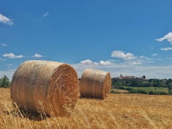 Hay bales on field against sky