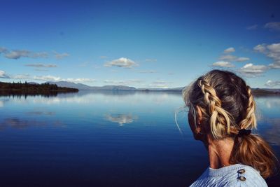 Rear view of woman looking at lake against sky