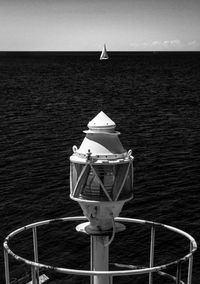 Sailboat sailing on sea against sky near lighthouse 