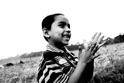 Portrait of happy boy standing on field against sky