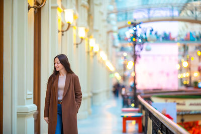 Beautiful smiling woman standing on footpath by building